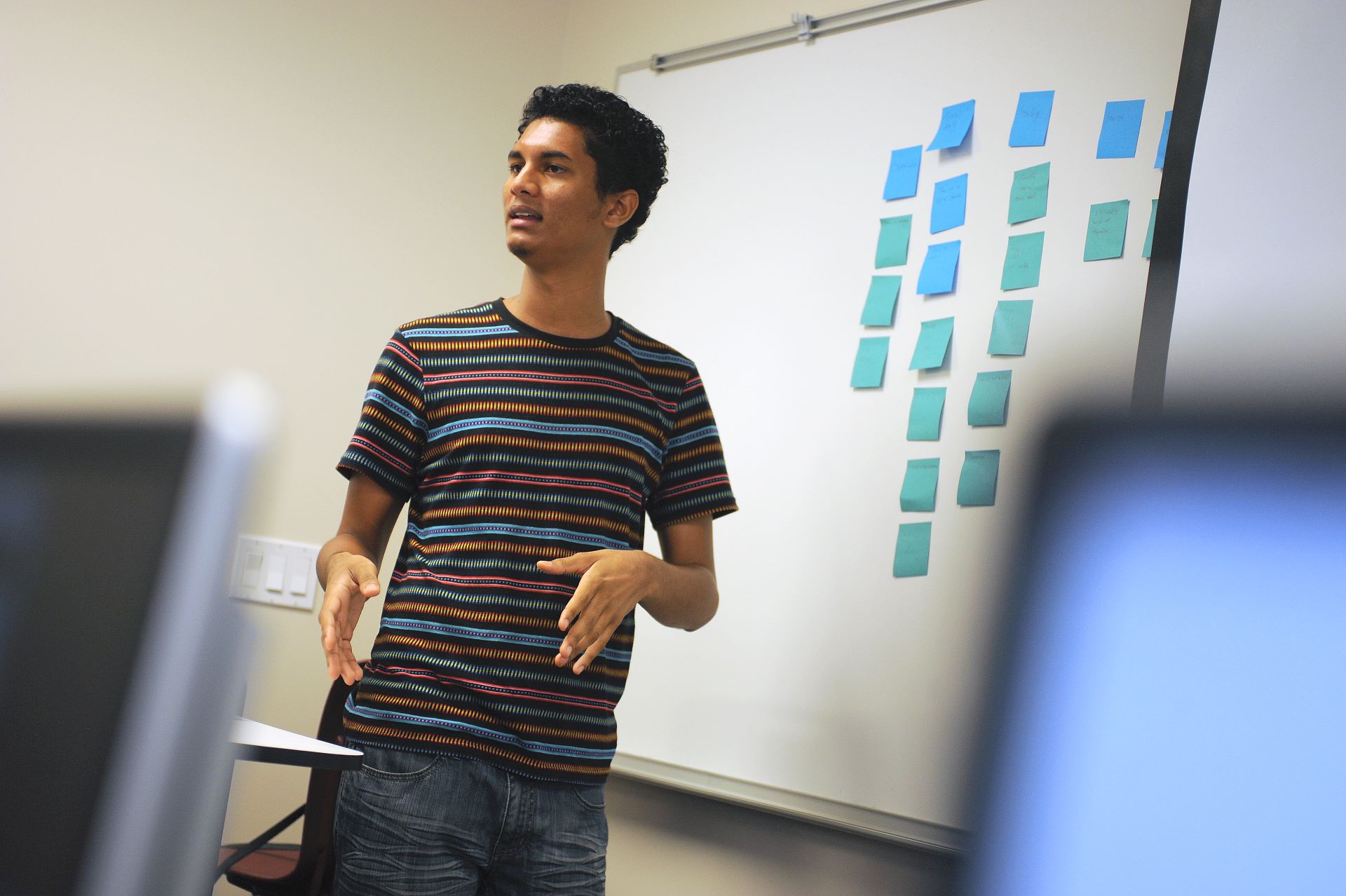 Student presenting in front of a whiteboard with sticky notes